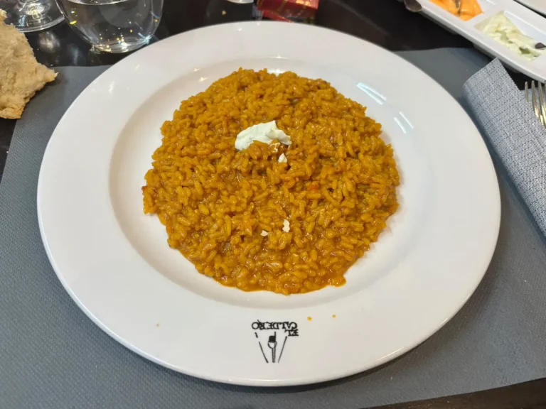 Arroz al caldero de mújol servido en plato con el logo de El Caldero, restaurante murciano en Madrid
